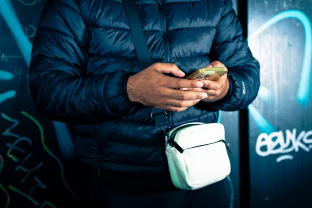 Image By Unsplash Nguồn: https://unsplash.com/fr/photos/un-homme-debout-devant-un-mur-tenant-un-telephone-portable-XQEjj-bIjL0